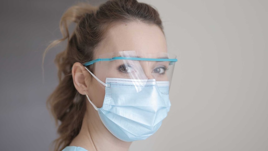 A woman in a ponytail wears a face mask and eye cover