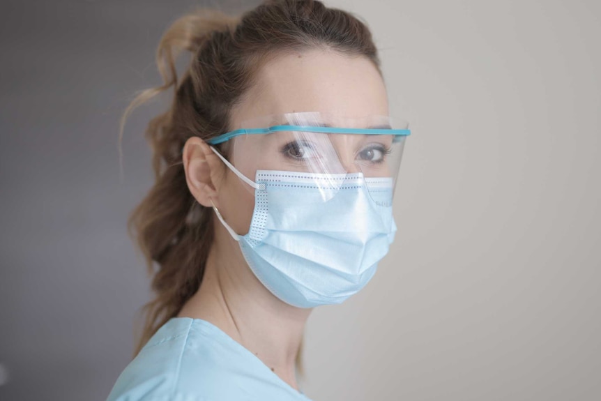 A woman in a ponytail wears a face mask and eye cover