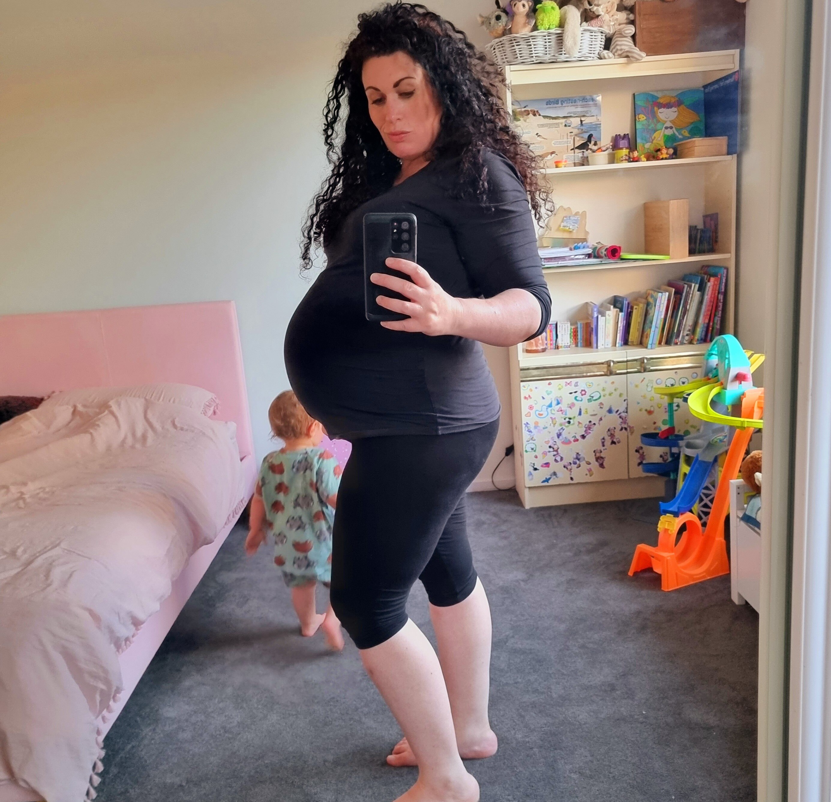 A heavily pregnant woman takes a selfie showing her belly