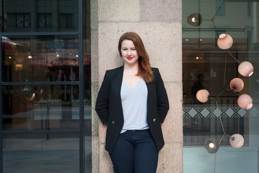 Hannah Kent leans against a building wall in the Adelaide CBD