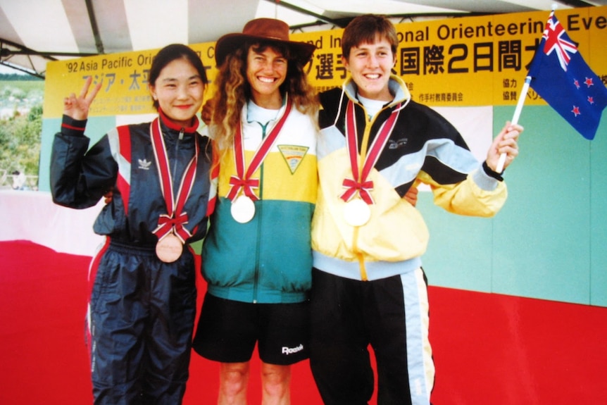 three women in athletic gear wearing medals