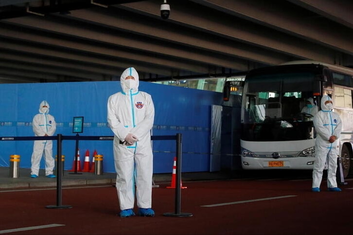 Men in protective suits stand guard for the  arrival of a World Health Organisation team.