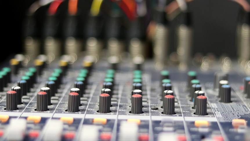 Knobs and faders on a sound mixing panel.