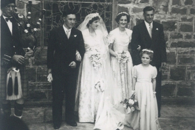 A 1940s wedding featuring a bride and groom with a bridesmaid, best man and flower girl.