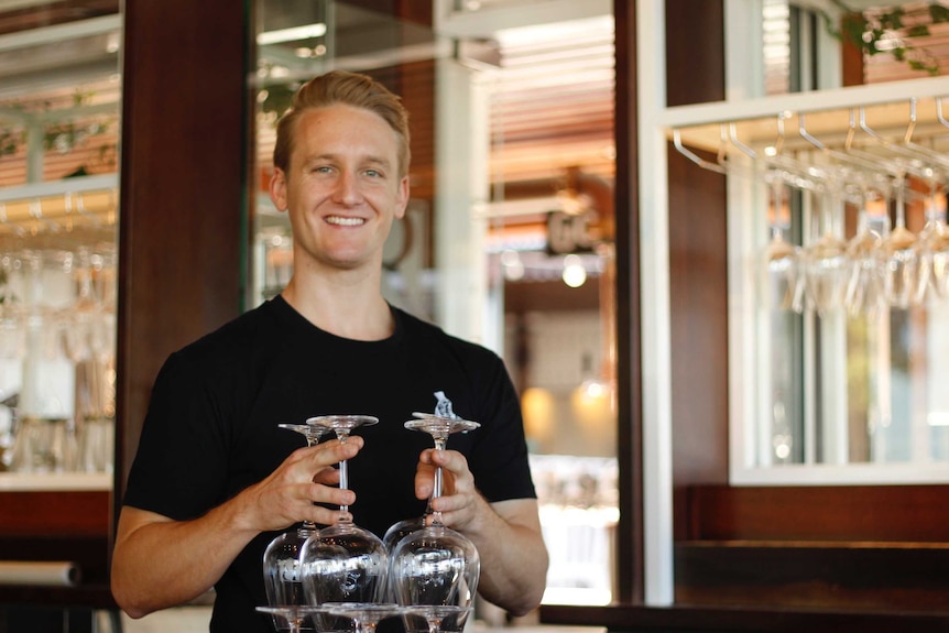 Man holds glasses in the bar of the Regatta Hotel.