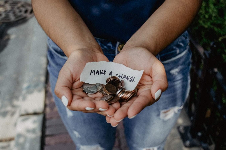 A handful of coins with a paper which reads, 'Make a Change'