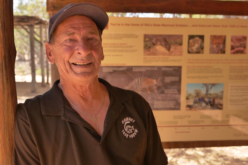 John Lawson stands in front of a numbat information sign in Dryandra