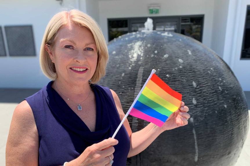 Trudi Murray stands with a rainbow flag at the Arcare aged care facility