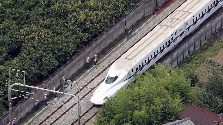 This aerial view shows a Nozomi 255 bullet train stopping near the Odawara station.