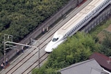 This aerial view shows a Nozomi 255 bullet train stopping near the Odawara station.