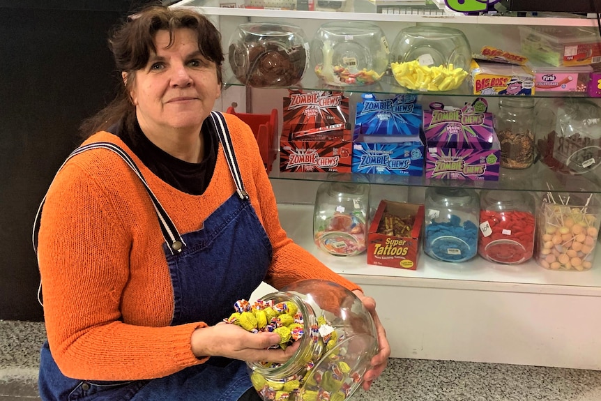 A woman holds a jar filled with Fantales lollies.