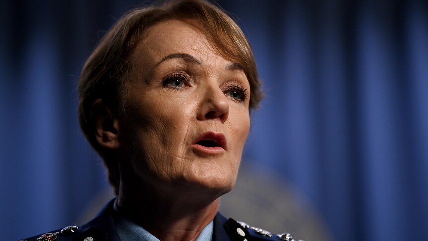 A close up photo of Police Commissioner Karen Webb, who has short dark hair, in front of blue curtains
