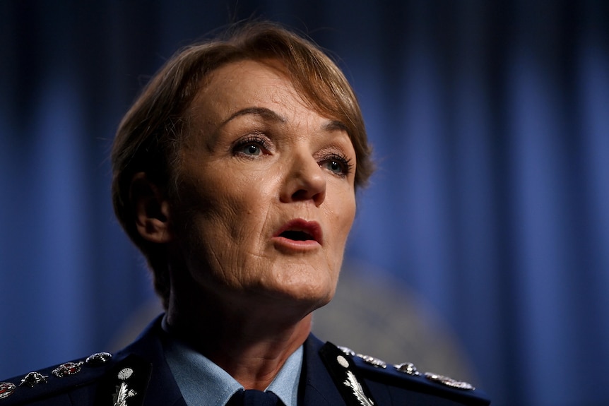 A close up photo of Police Commissioner Karen Webb, who has short dark hair, in front of blue curtains