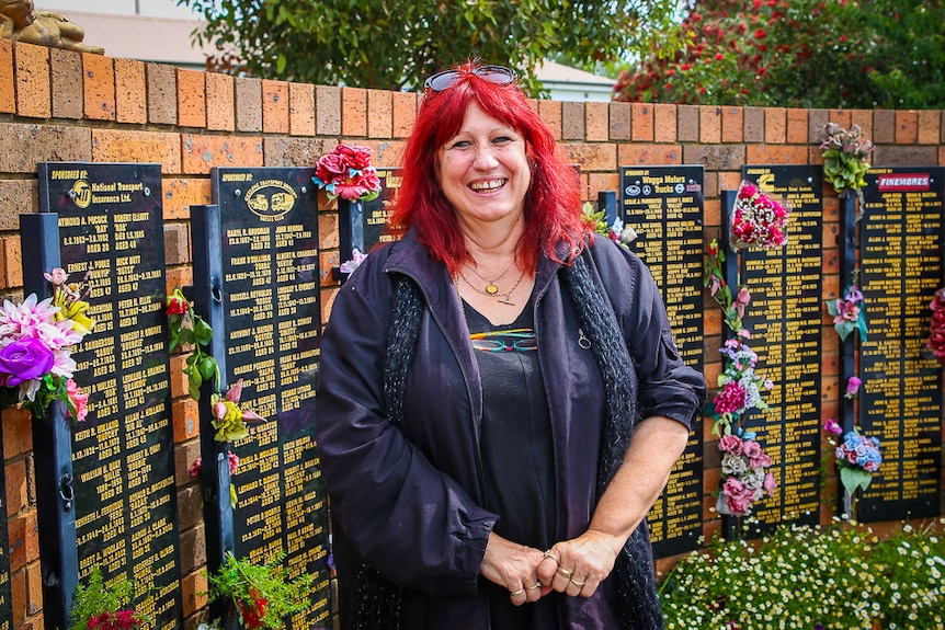 Liz Martin, chief executive of the National Road Transport Hall of Fame, stands in front of a memorial wall.