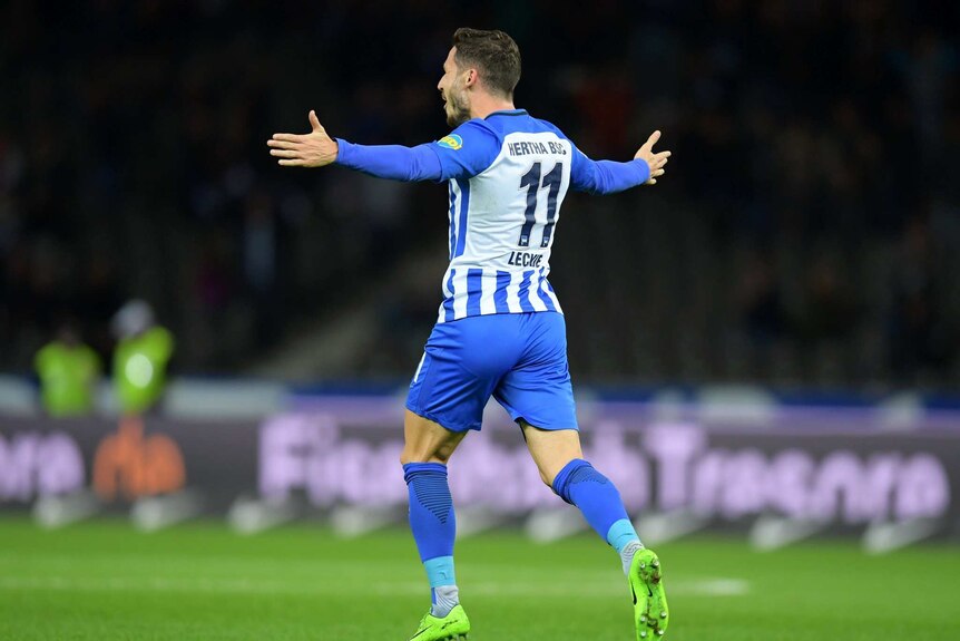 Mathew Leckie runs with his arms outstretched during a game.