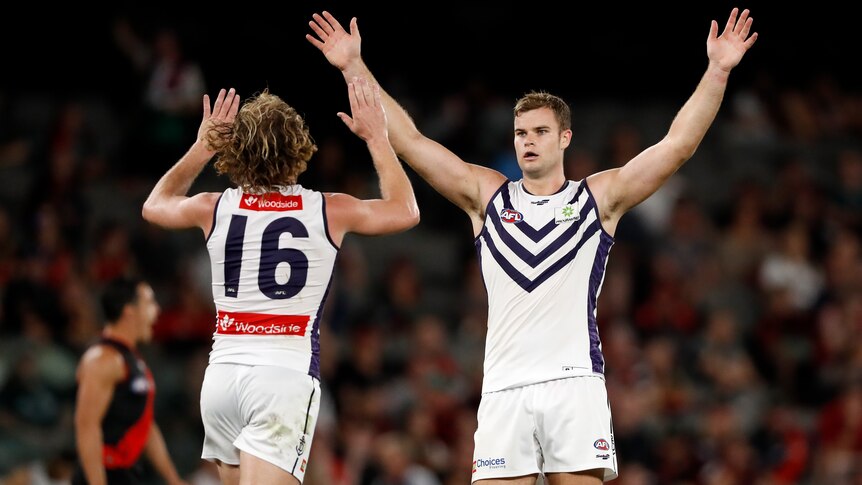 Sean Darcy stands with his arms in the air as David Mundy runs to congratulate him