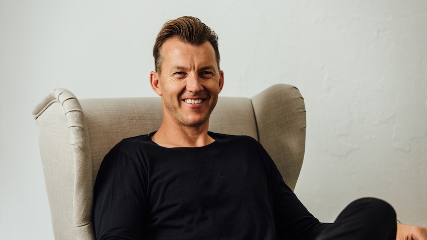 Mid shot of cricketer Brett Lee seated and smiling at the camera.