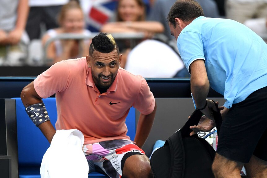 A tennis player leans forward and grimaces during a medical timeout at the Australian Open.