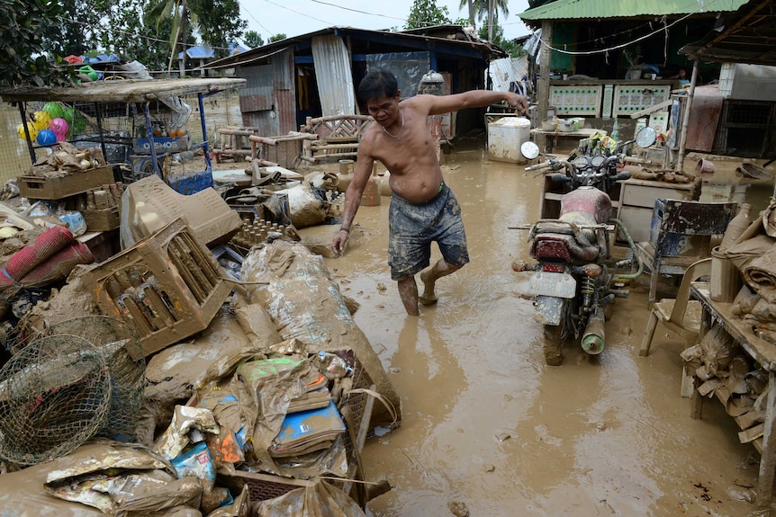 A man walks amongst mud-filled belongings after Typhoon Koppu