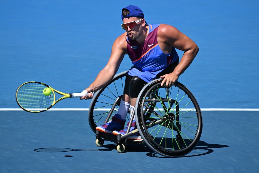 An Australian male tennis player hits a forehand in a quad wheelchair singles match.