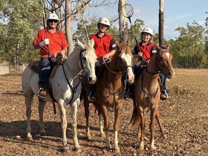 Tree people on horseback smile at the camera with polo cross sticks in hand