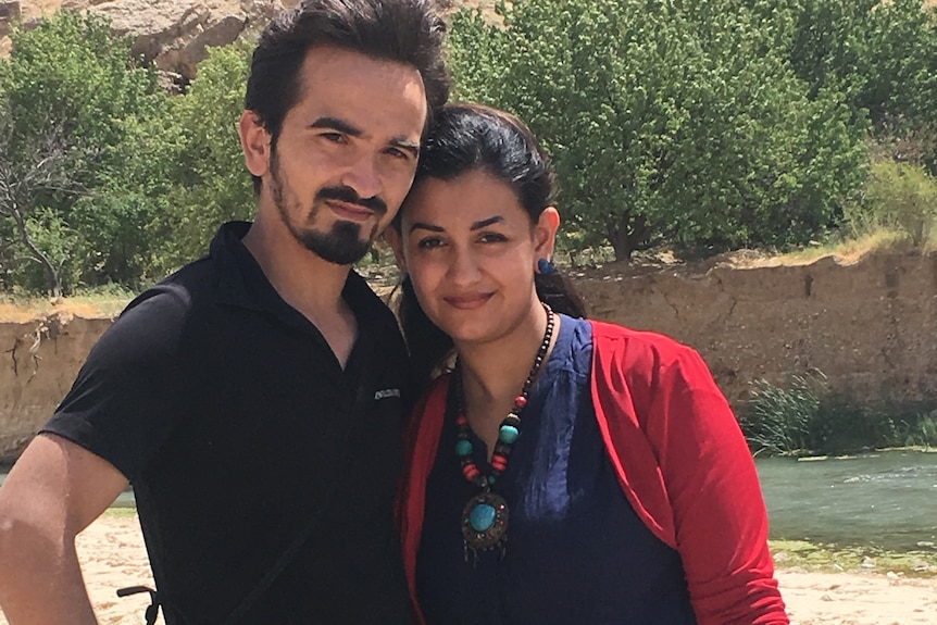 Young dark-haired married couple, posing against a mountainous background