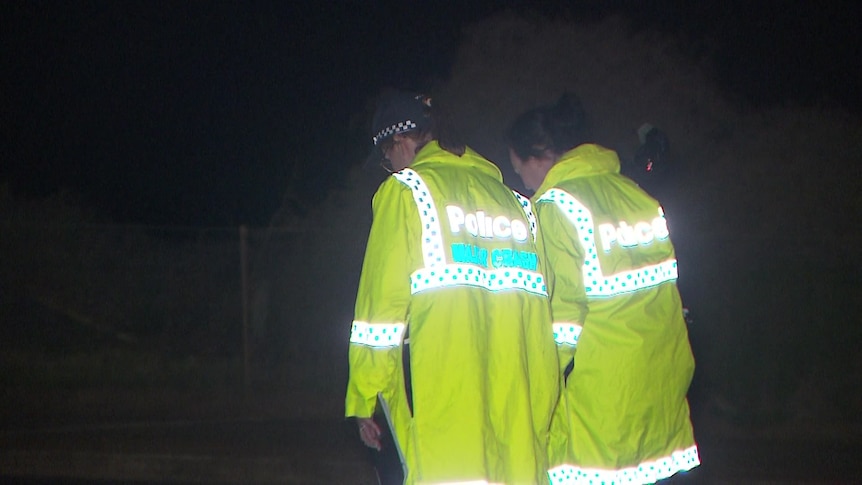 Two police officers wearing yellow hi-vis jackets in the dark