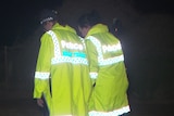 Two police officers wearing yellow hi-vis jackets in the dark