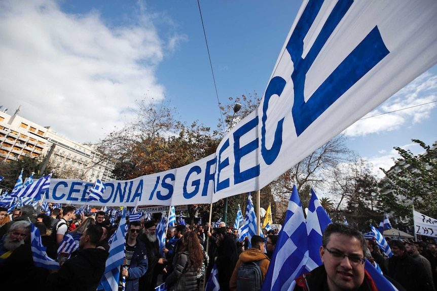 A banner reads "Macedonia is Greece" as hundreds of demonstrators hold Greek flags during a rally in Athens.