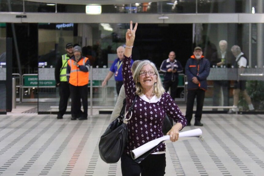 A woman throws up two wingers and celebrates the fact Schapelle Corby was not spotted by media leaving Brisbane International