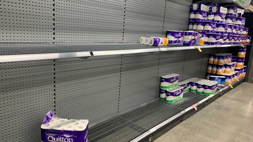 Half-filled shelves of toilet paper at a supermarket.