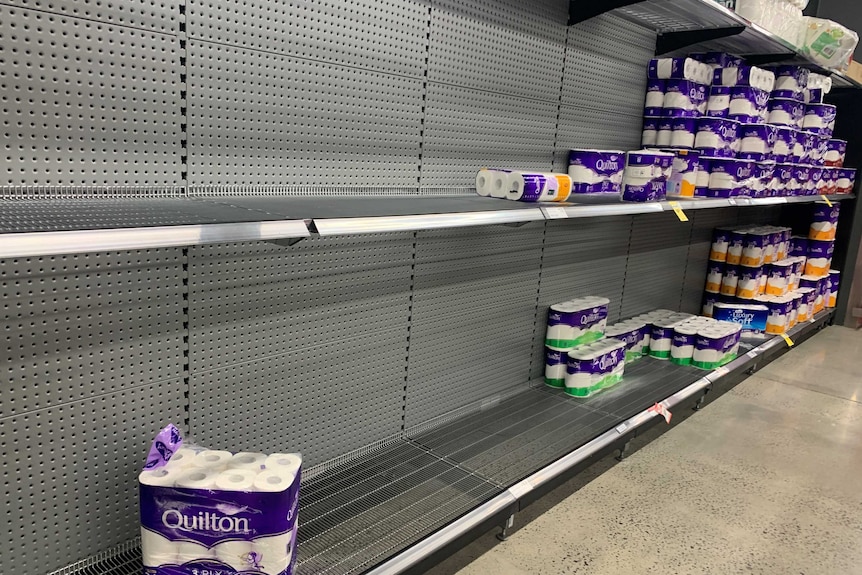 Half-filled shelves of toilet paper at a supermarket.