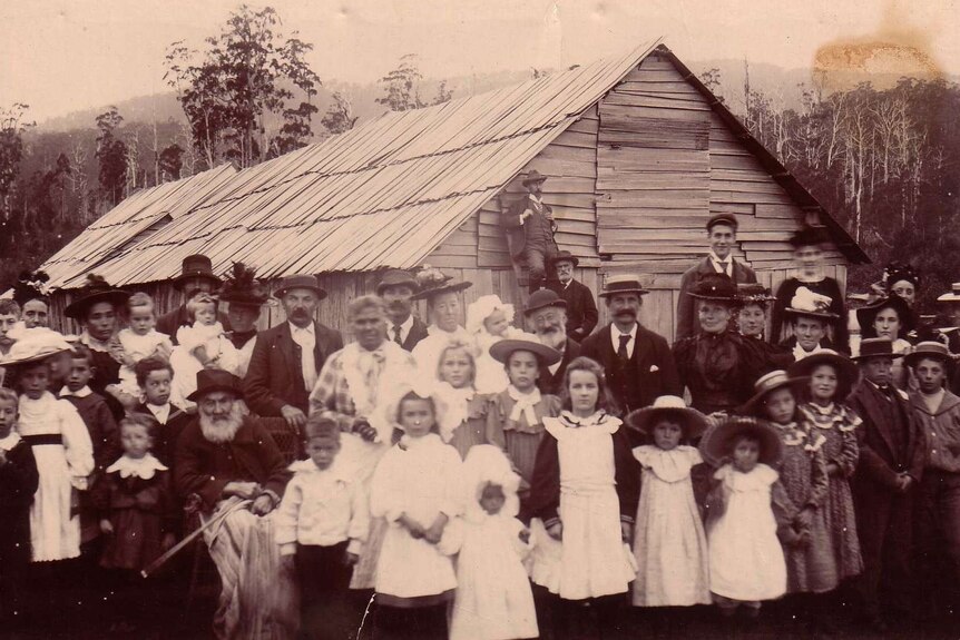 A sepia-coloured photo of Fanny Smith as an old woman and about 30 of her extended family standing in front of a barn.
