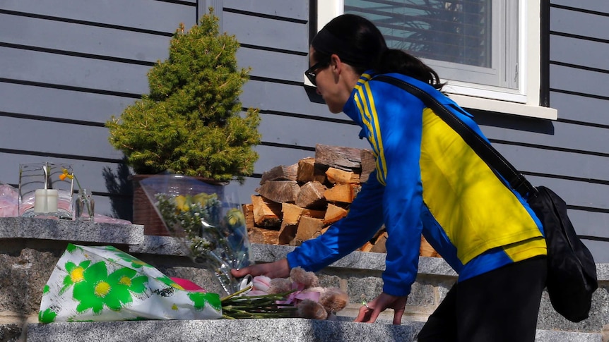 A Boston Marathon runner leaves flowers on the doorstep of a bombing victim