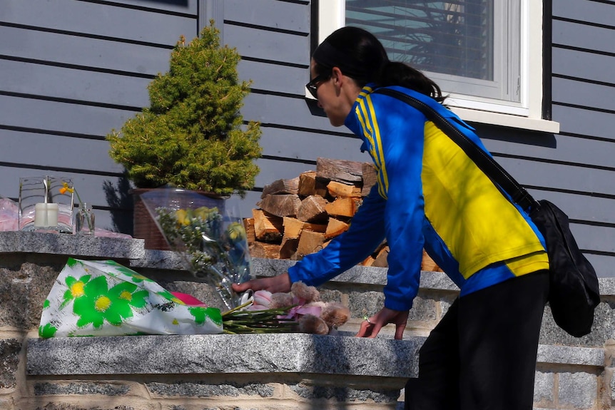 A Boston Marathon runner leaves flowers on the doorstep of a bombing victim