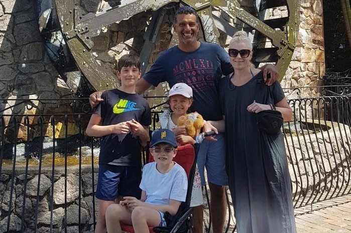 Two adults and three children in front of an old building