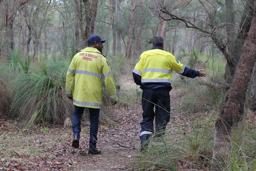 two firefighters in high viz walking along in bushland