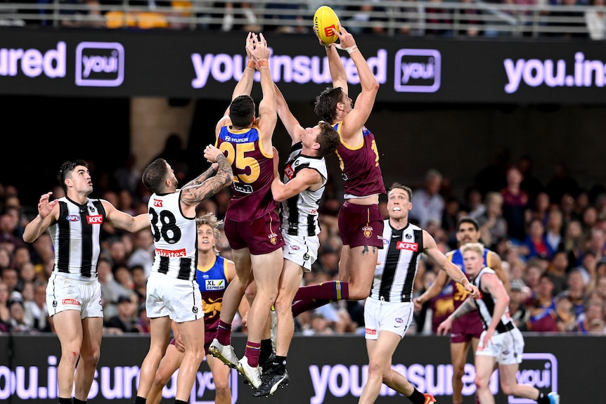 Joe Daniher is highest at the front of a big pack of Lions and Pies players and has the ball in his hands