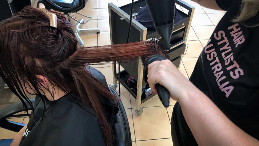 A hair salon client has their hair blow dried