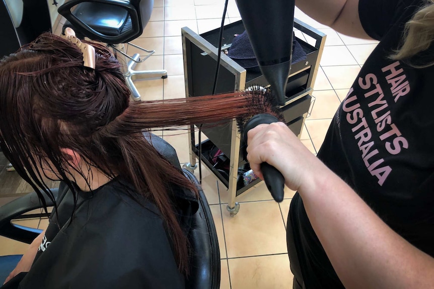 A hair salon client has their hair blowdried