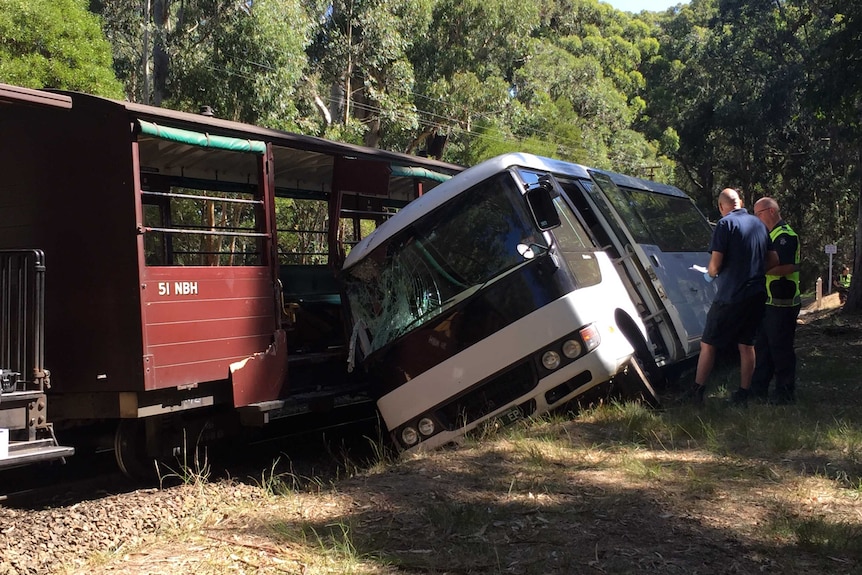 A minibus leaning against the side of the Puffing Billy tourist train.