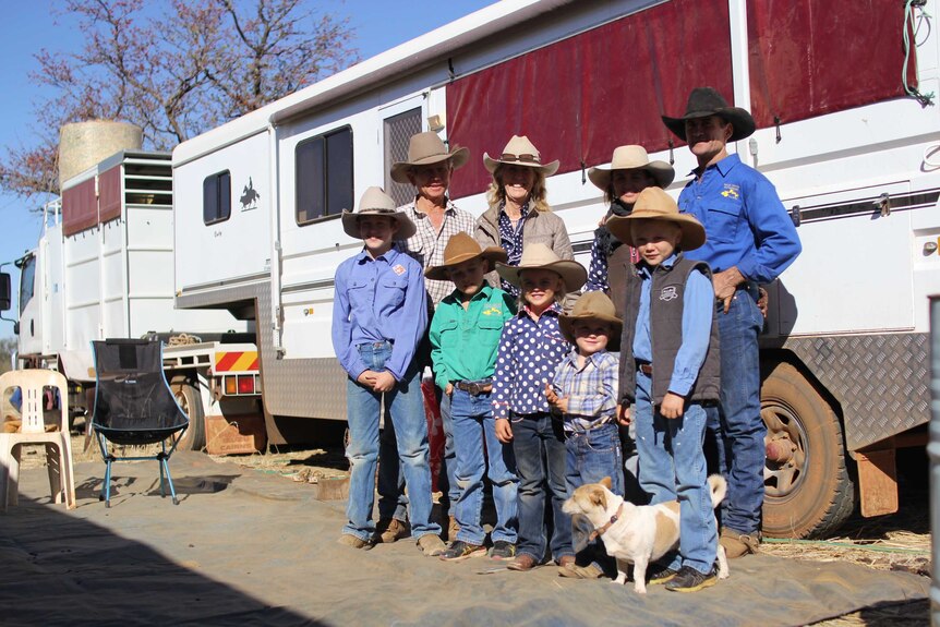 The Daley family of nine and their little dog stands in front of their horse truck
