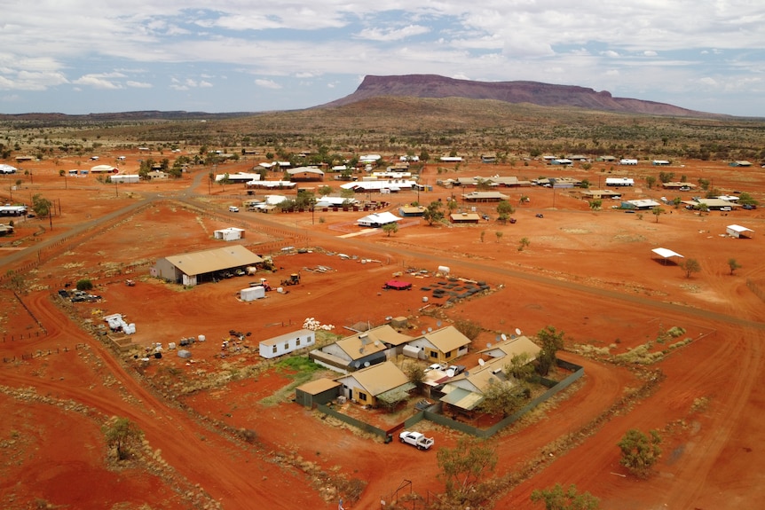 An aerial view of a remote, red dirt town, with a mountain visible in the distance