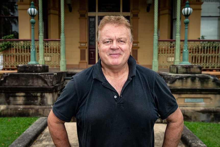 A man stands in front of a federation home and looks at the camera.