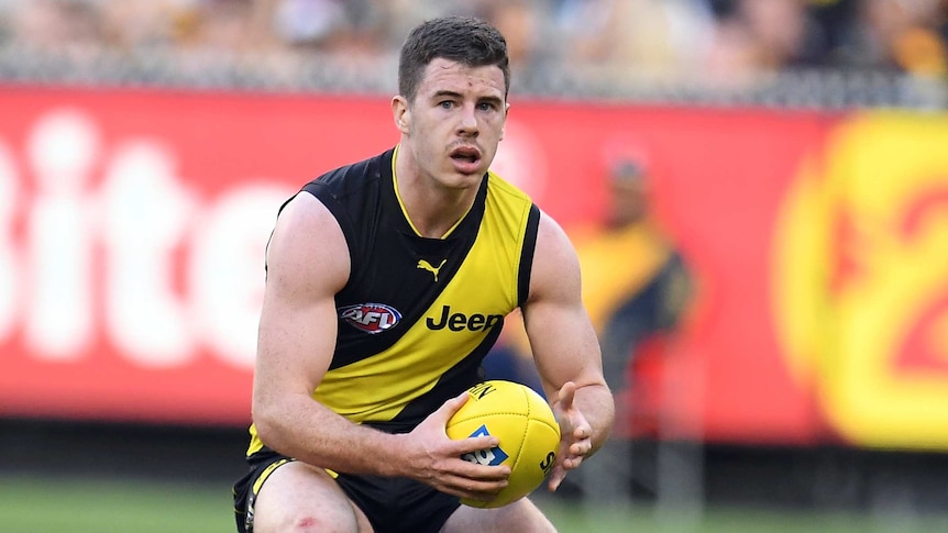 Jack Higgins moves to grip the Sherrin with two hands during an AFL game for the Richmond Tigers.