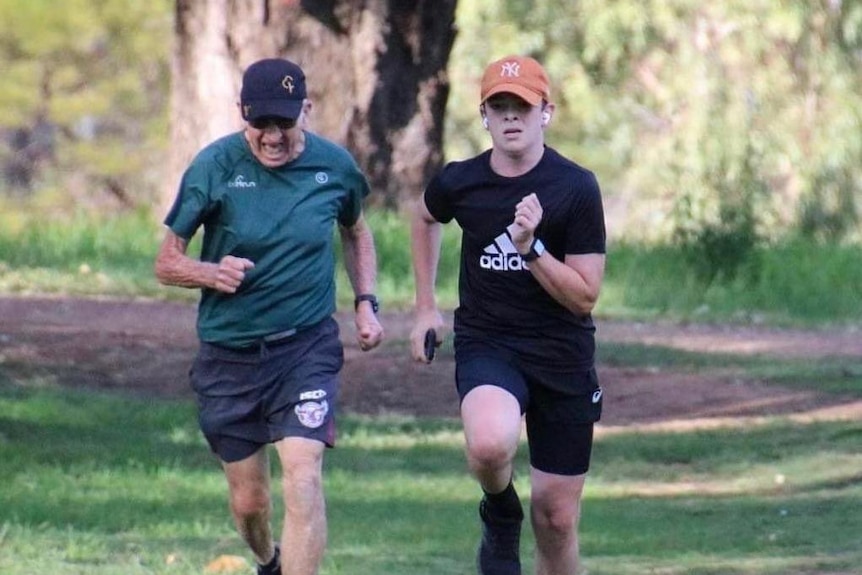 An 83-year-old man and young boy run together in a park