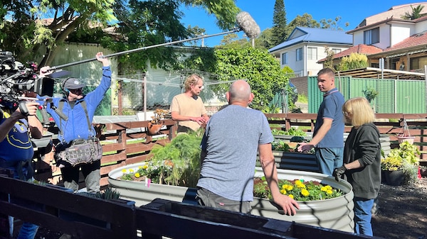 People being filled in a garden standing around a raised vegie bed.