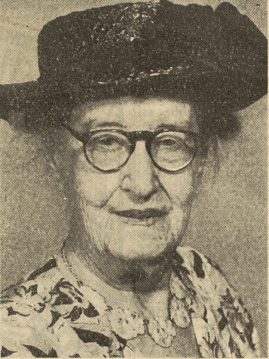 A black and white photo of an elderly, bespectacled woman wearing a hat.