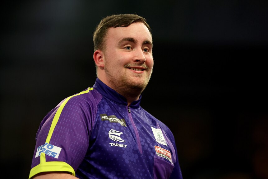 A darts player smiles after a victory