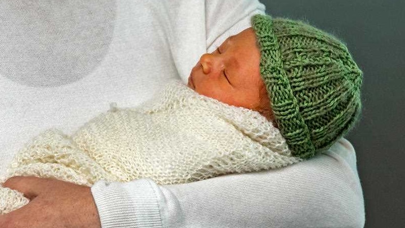 Neve Te Aroha Ardern Gayford wrapped in a cream knitted blanket and wearing a green knitted hat